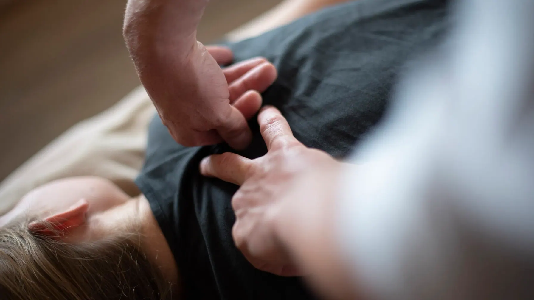 Therapist providing focused therapeutic massage to a client’s upper back and shoulder